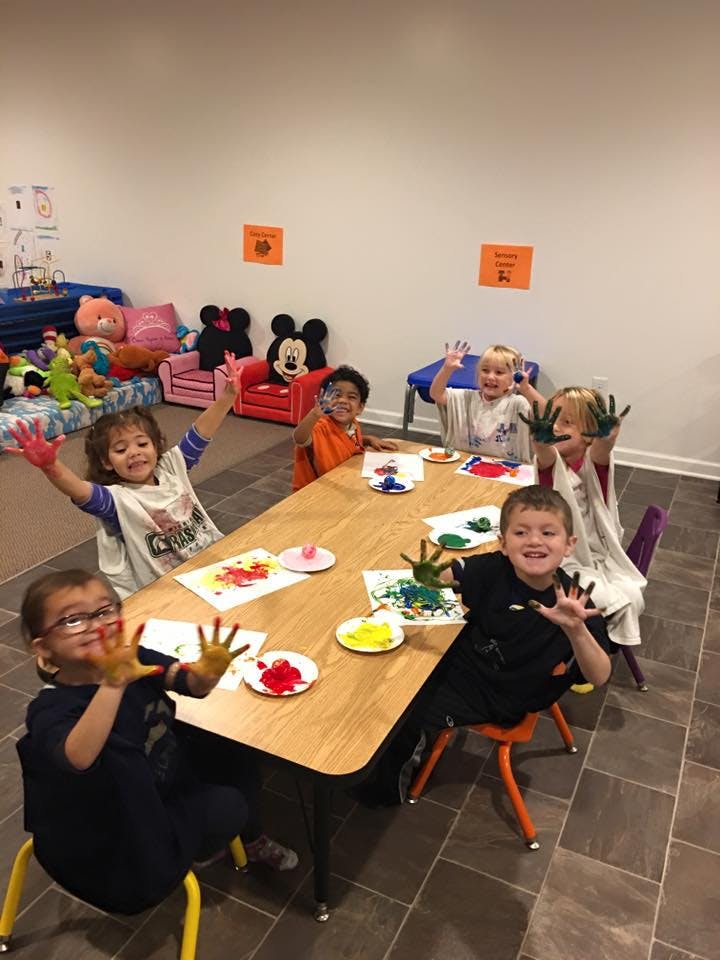Children at a table with paint on their hands