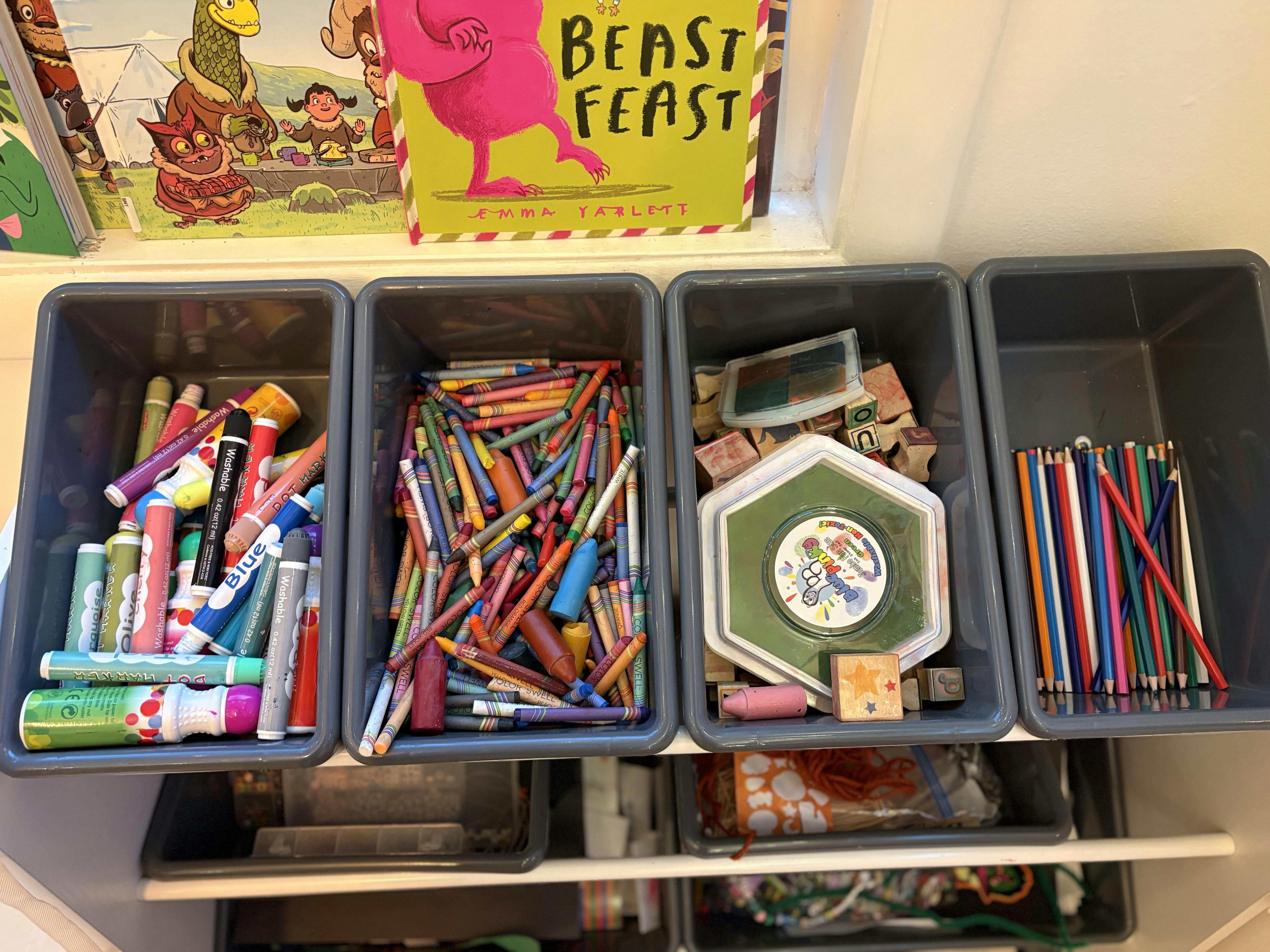 Craft supplies in bins with markers, crayons, stamps, and colored pencils