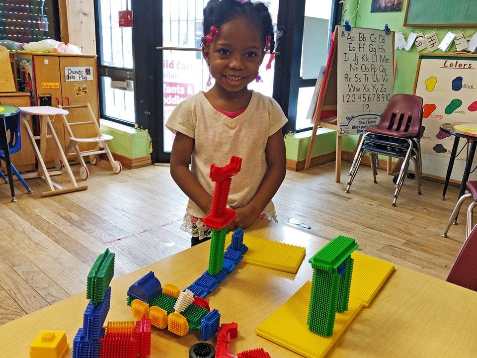 Child standing behind a table with colorful building blocks
