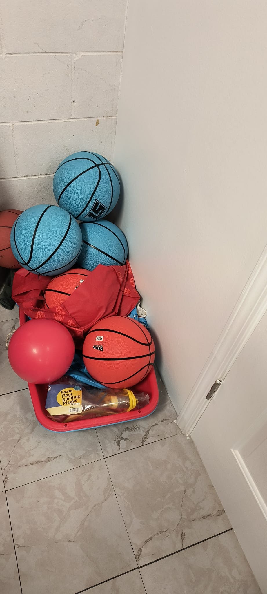 Blue and orange basketballs in a red bin