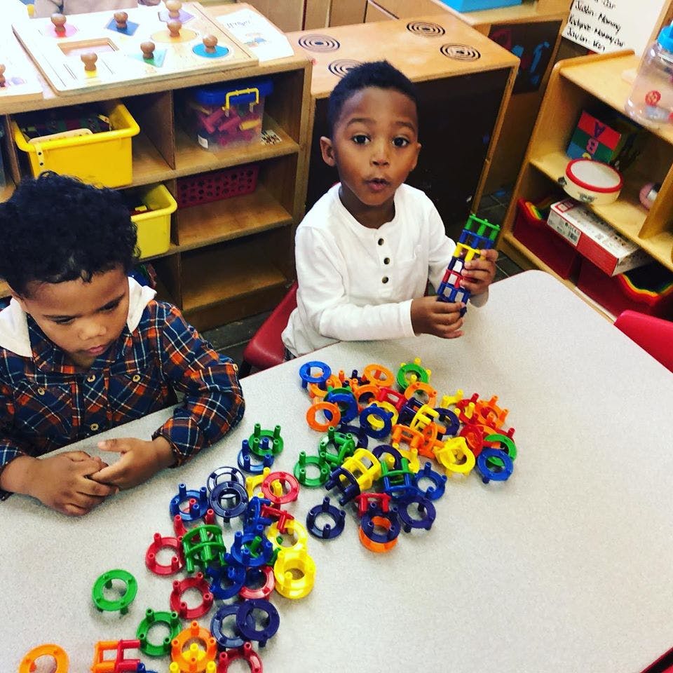 Two children playing with colorful interlocking toys at a table