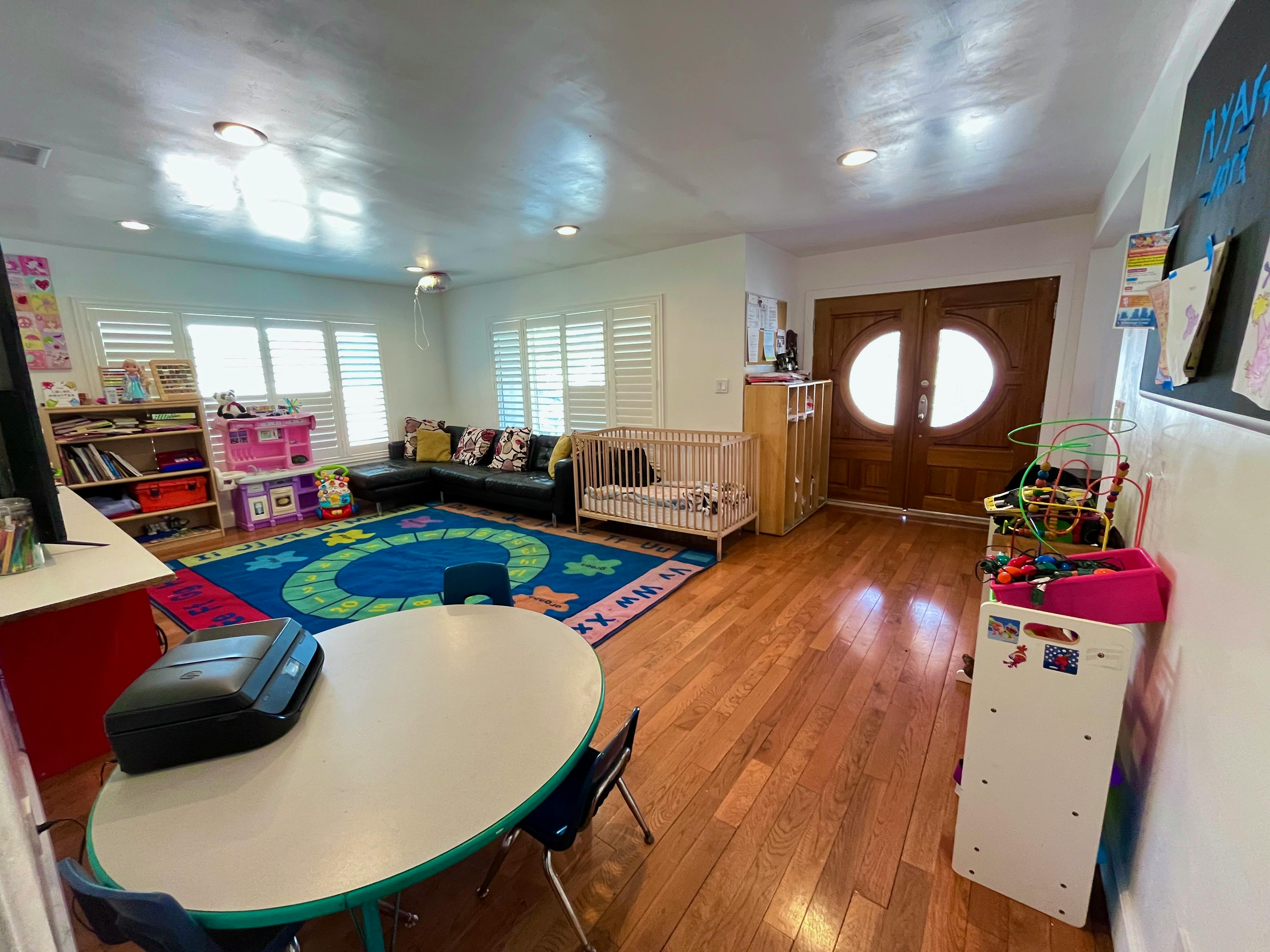 Playroom with a blue rug, small table and chairs, crib, and sofa