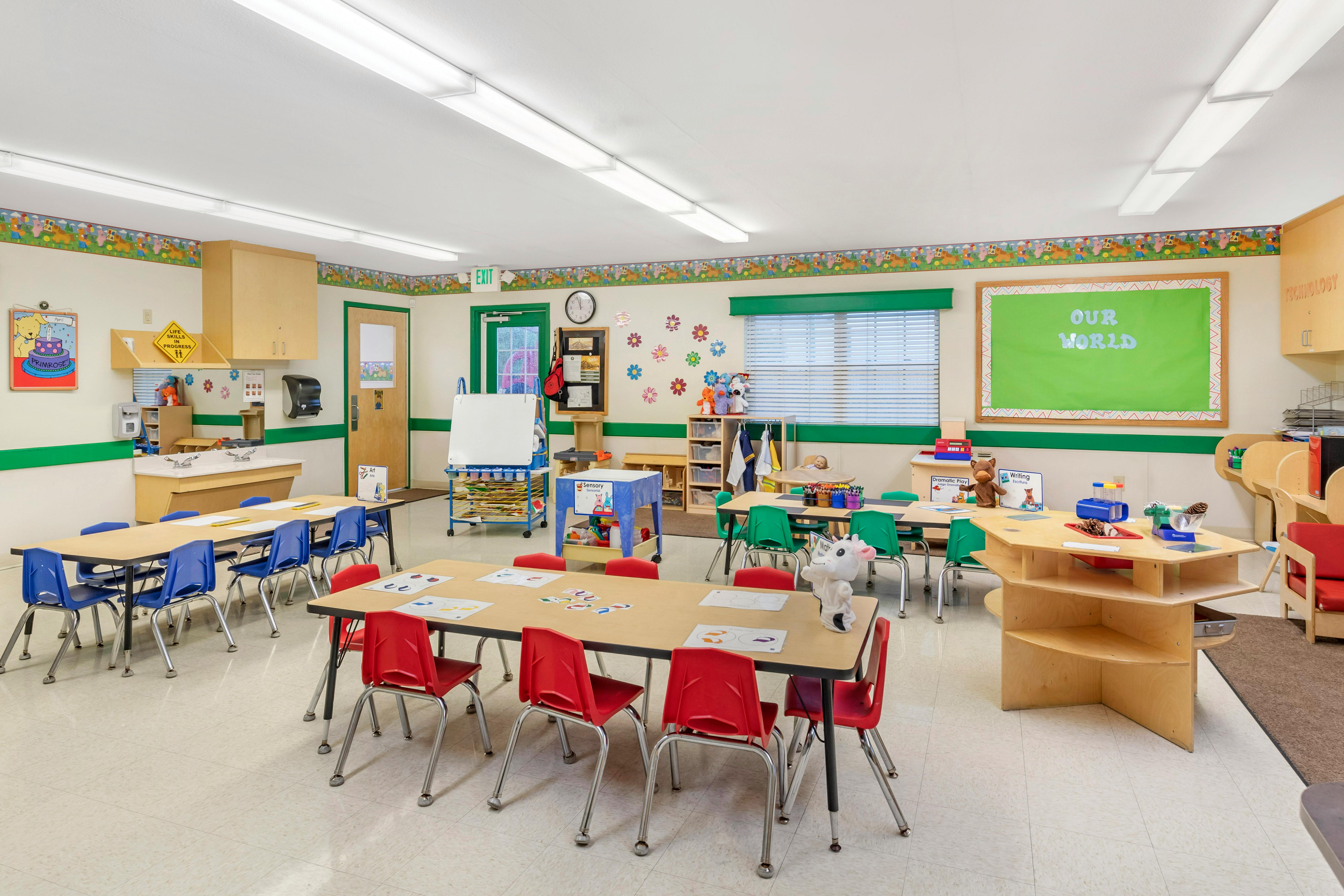 A colorful empty classroom with tables, chairs, and various learning stations