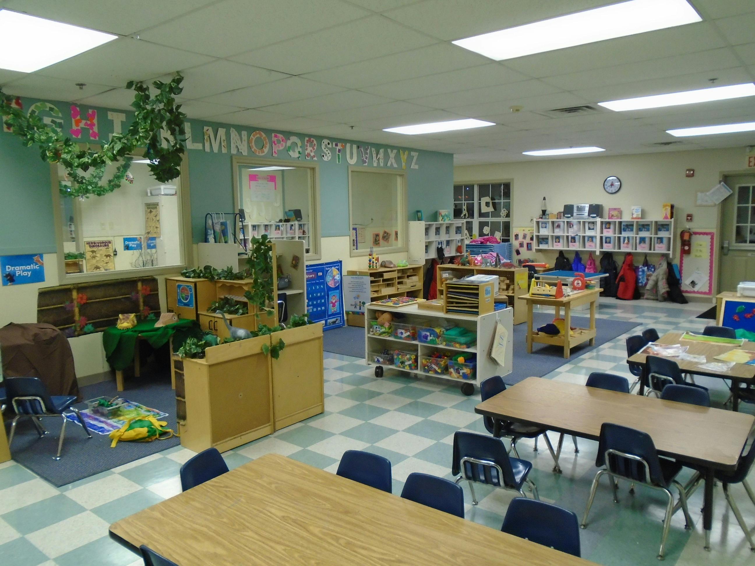 Classroom with small tables and chairs, shelves, and decorations on the wall