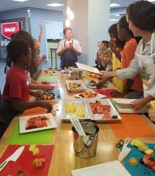 Adult and children preparing food at a long table