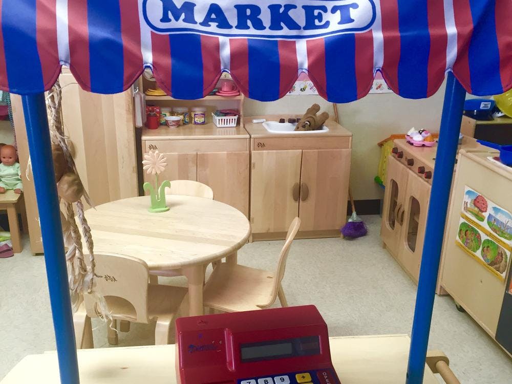 Play market stall with a red and blue striped awning and a toy cash register