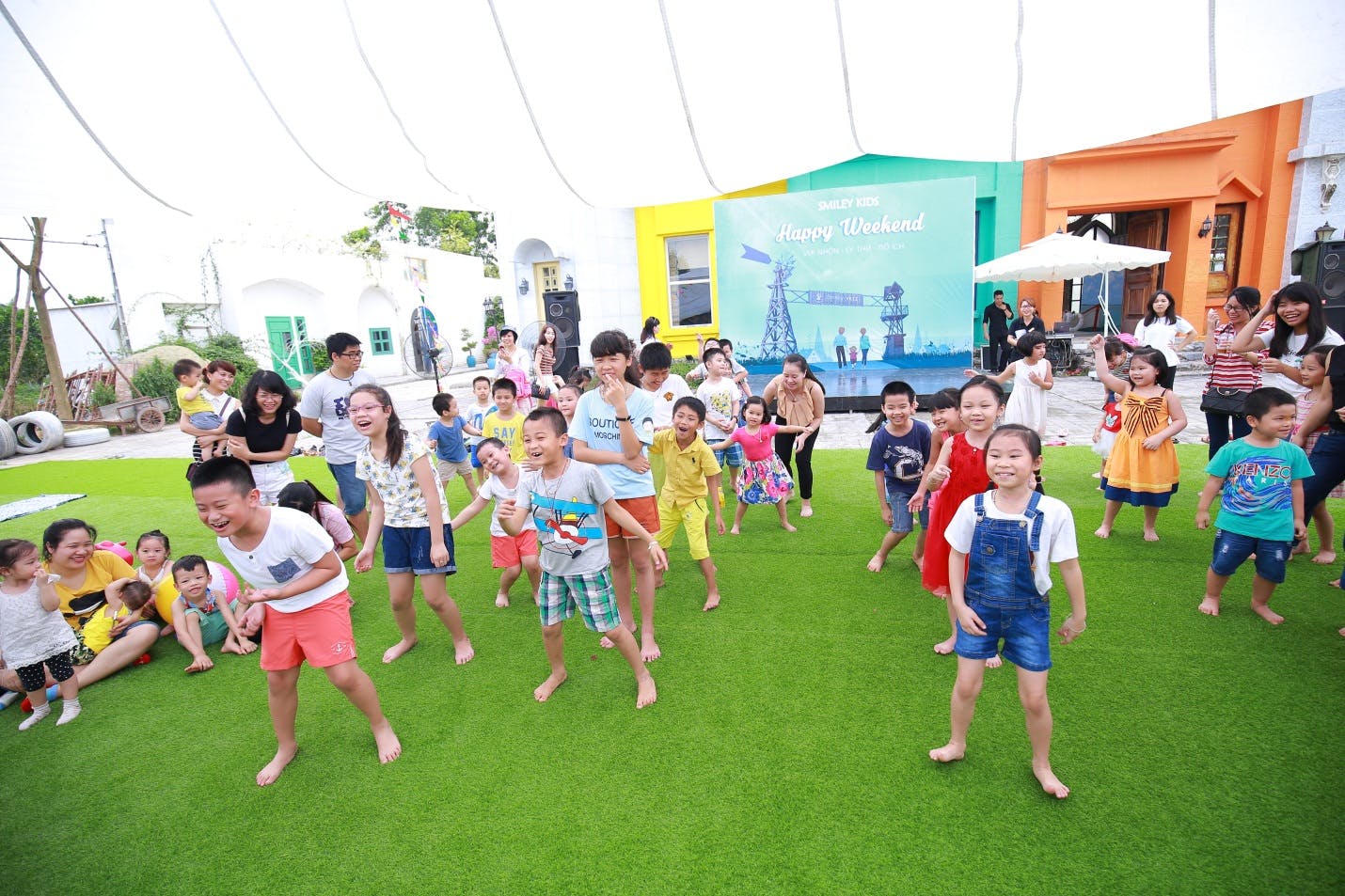Many children and adults playing on a green lawn