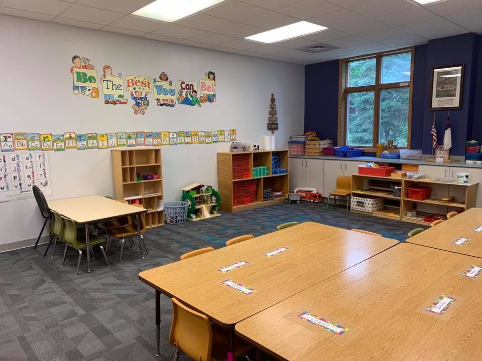 Empty classroom with tables, chairs, and shelves