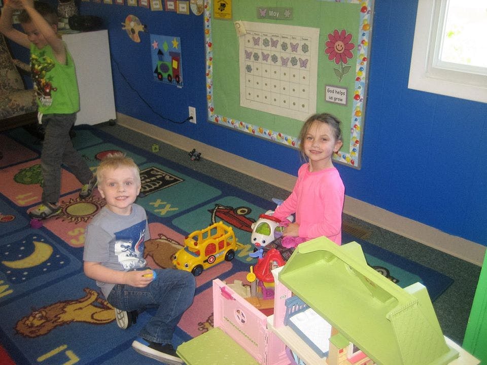 Two children playing with toys on a colorful rug