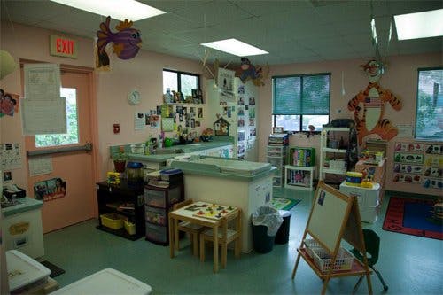 Classroom with small tables, chairs, and an easel