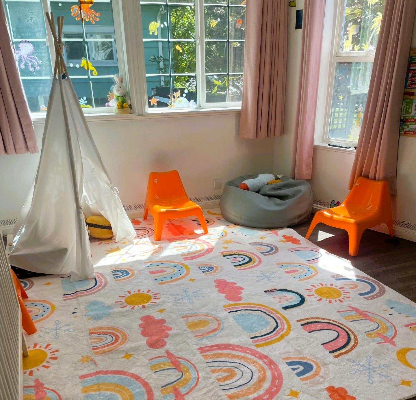Playroom with a teepee, beanbag, small chairs, and a rainbow-patterned rug
