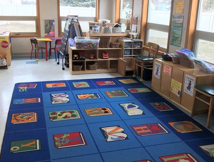 Classroom with a blue rug featuring colorful book designs