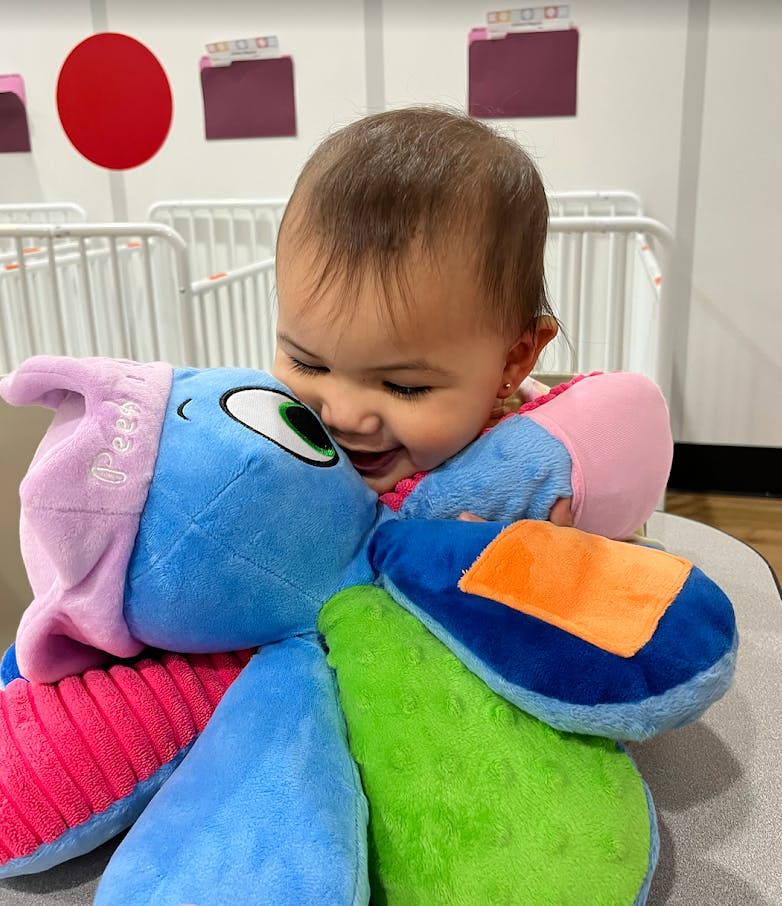 Child playing with a colorful plush toy