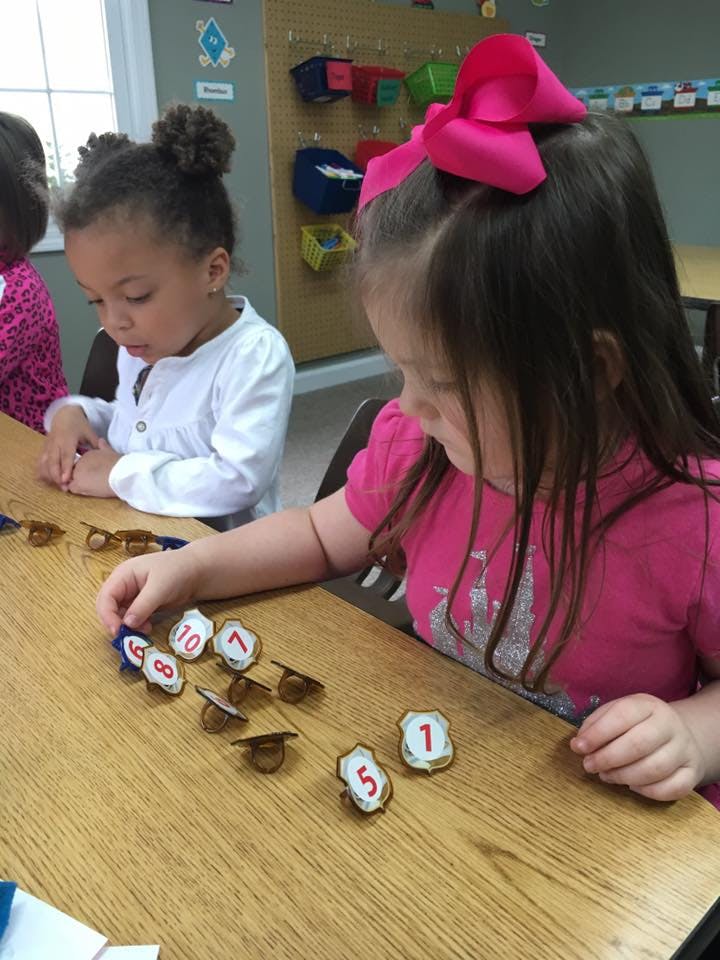 Two children playing with number tokens at a table