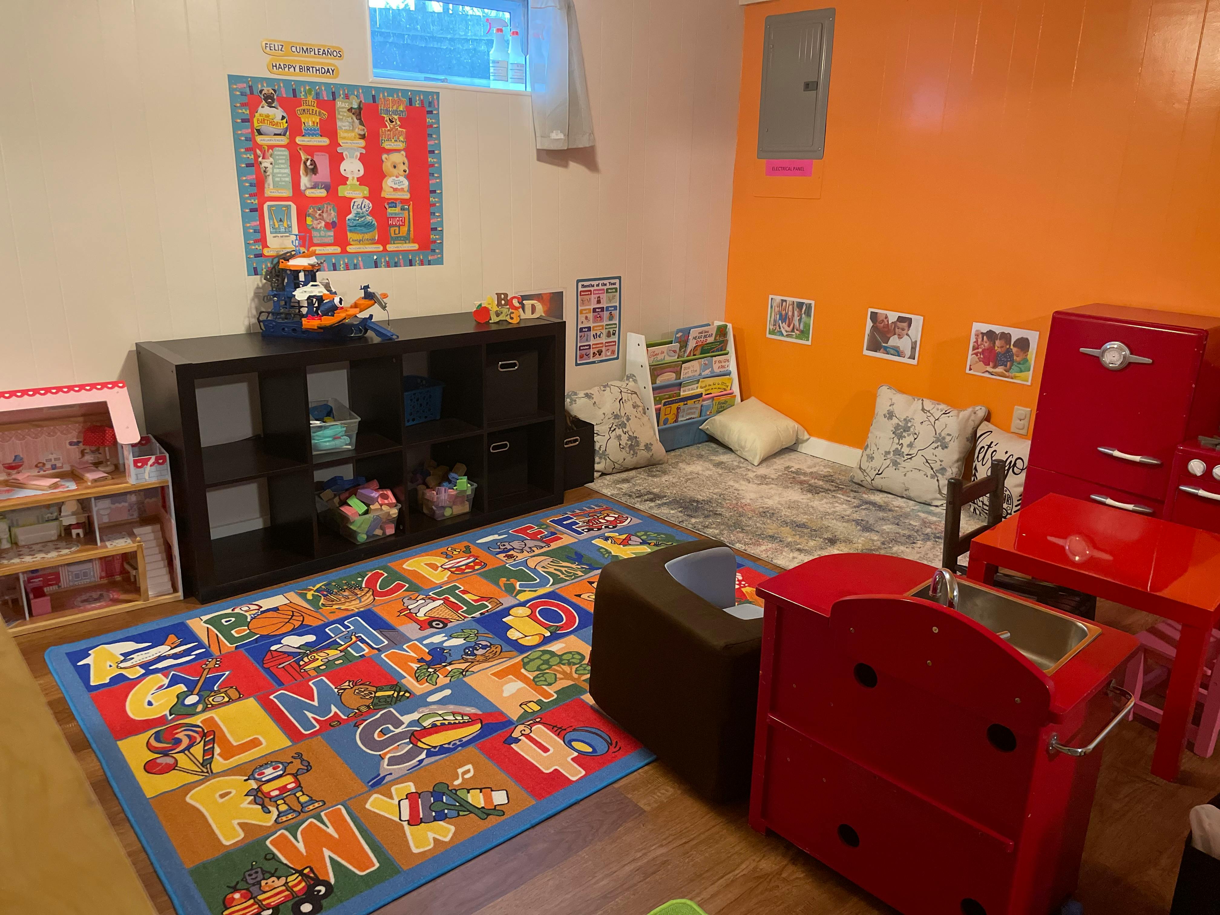 Playroom with alphabet rug, toy shelf, and red play kitchen