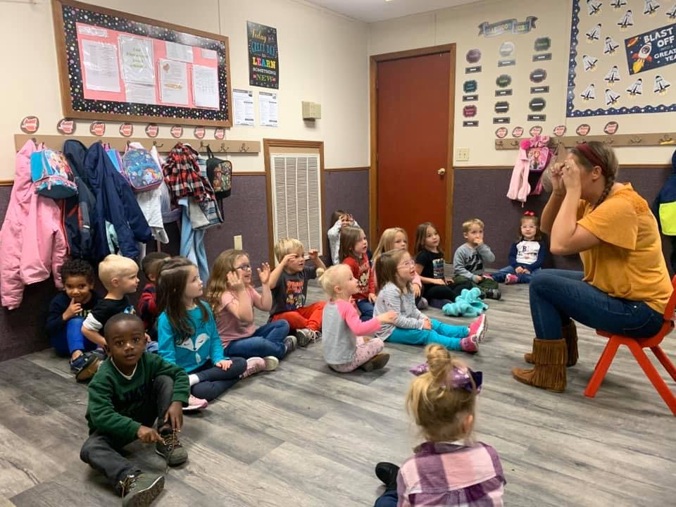 Adult and children sitting on floor in a classroom