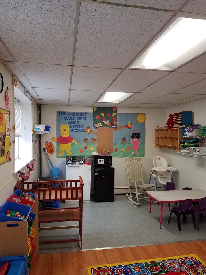 Childcare room with crib, small table and chairs, and wall decorations