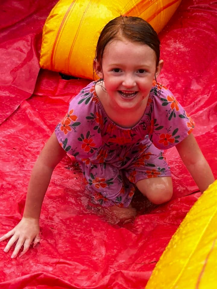 Child kneeling on a wet red surface