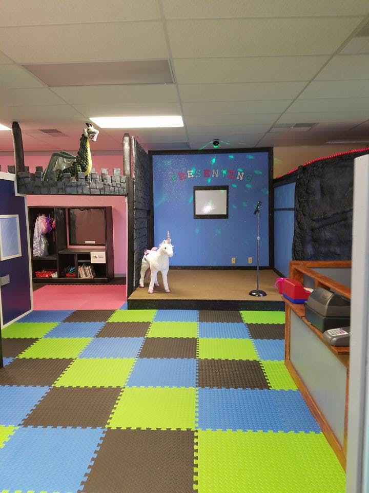 Indoor play area with checkered floor, stage, unicorn, and dragon decoration