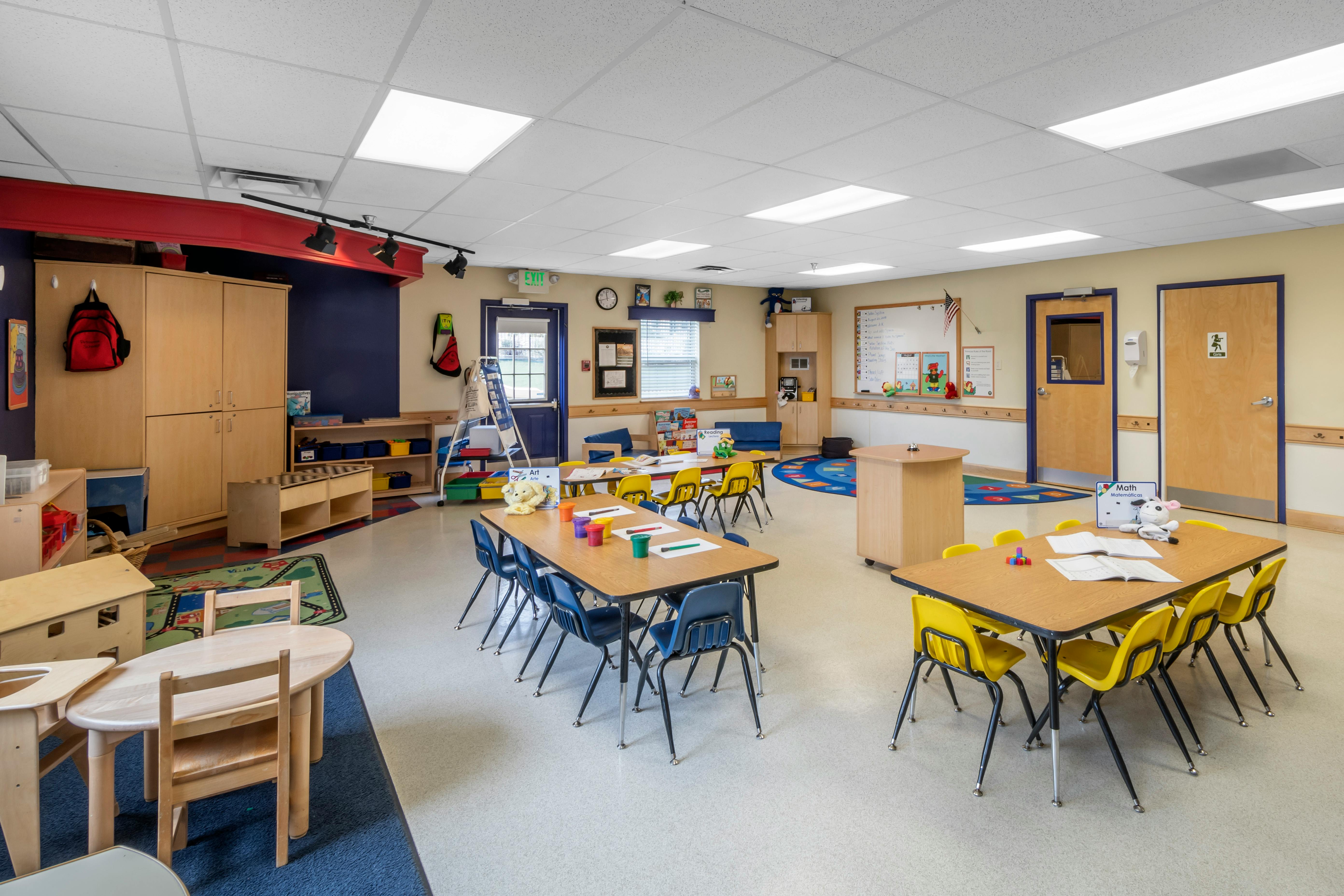 An empty early childhood classroom with multiple small tables and chairs