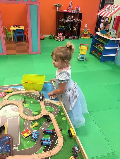 Child playing with a toy train set on a green mat