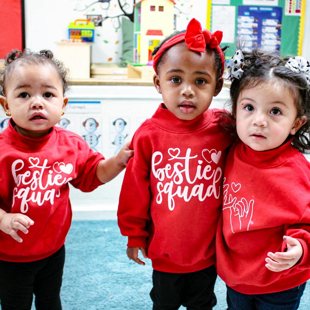 Three children in red "Bestie Squad" sweatshirts standing together