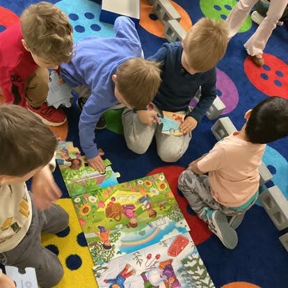 Children sitting on a rug and assembling a floor puzzle