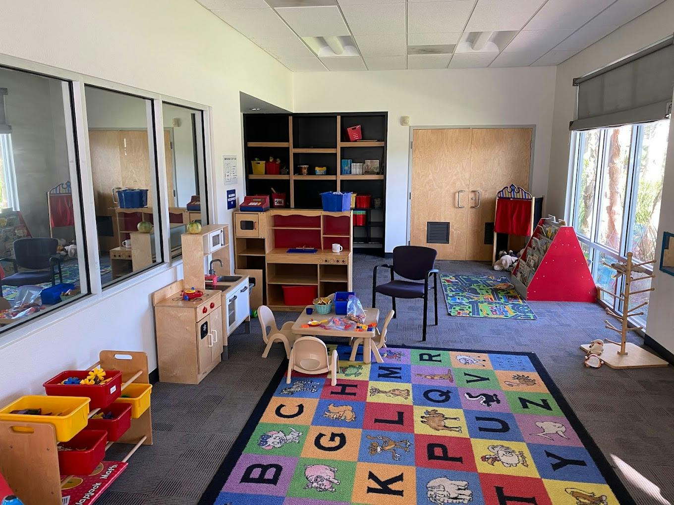 Playroom with alphabet rug, small table and chairs, and toy kitchen