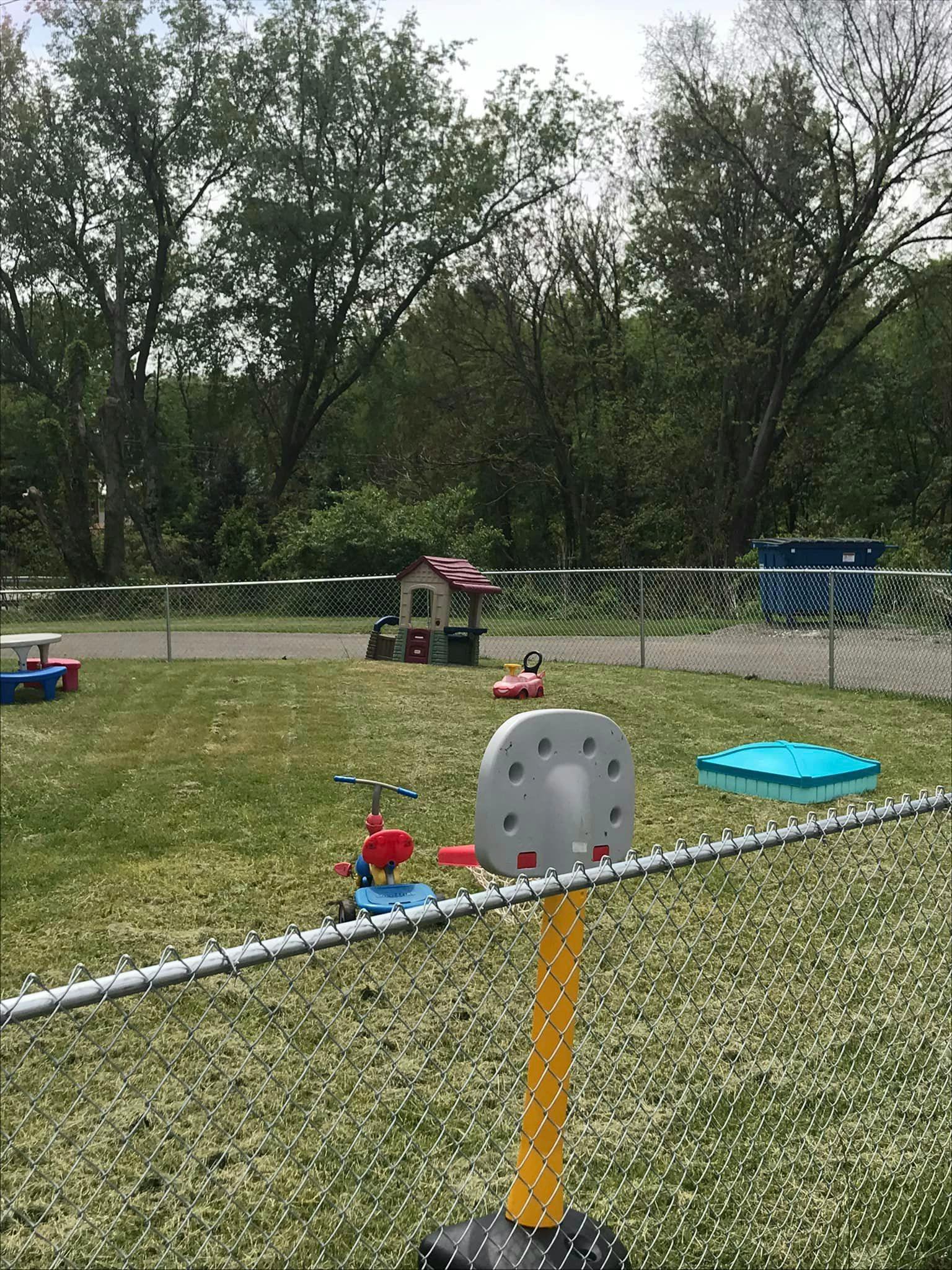 Playground with a small playhouse, ride-on toys, and a basketball hoop