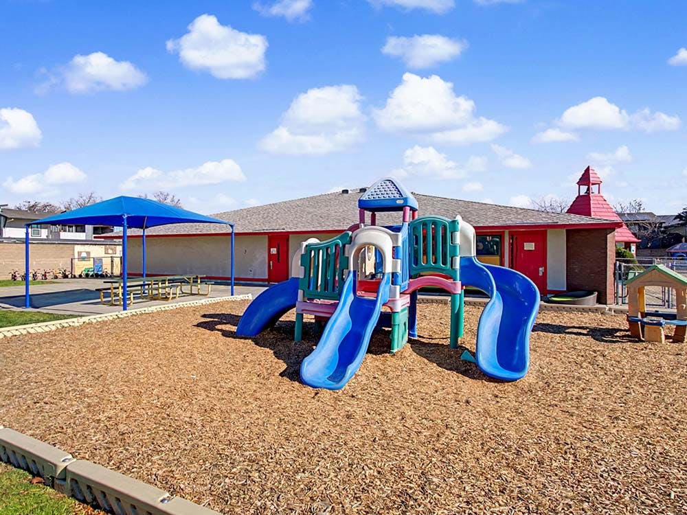 Colorful outdoor playground with slides on wood chips, a covered picnic area