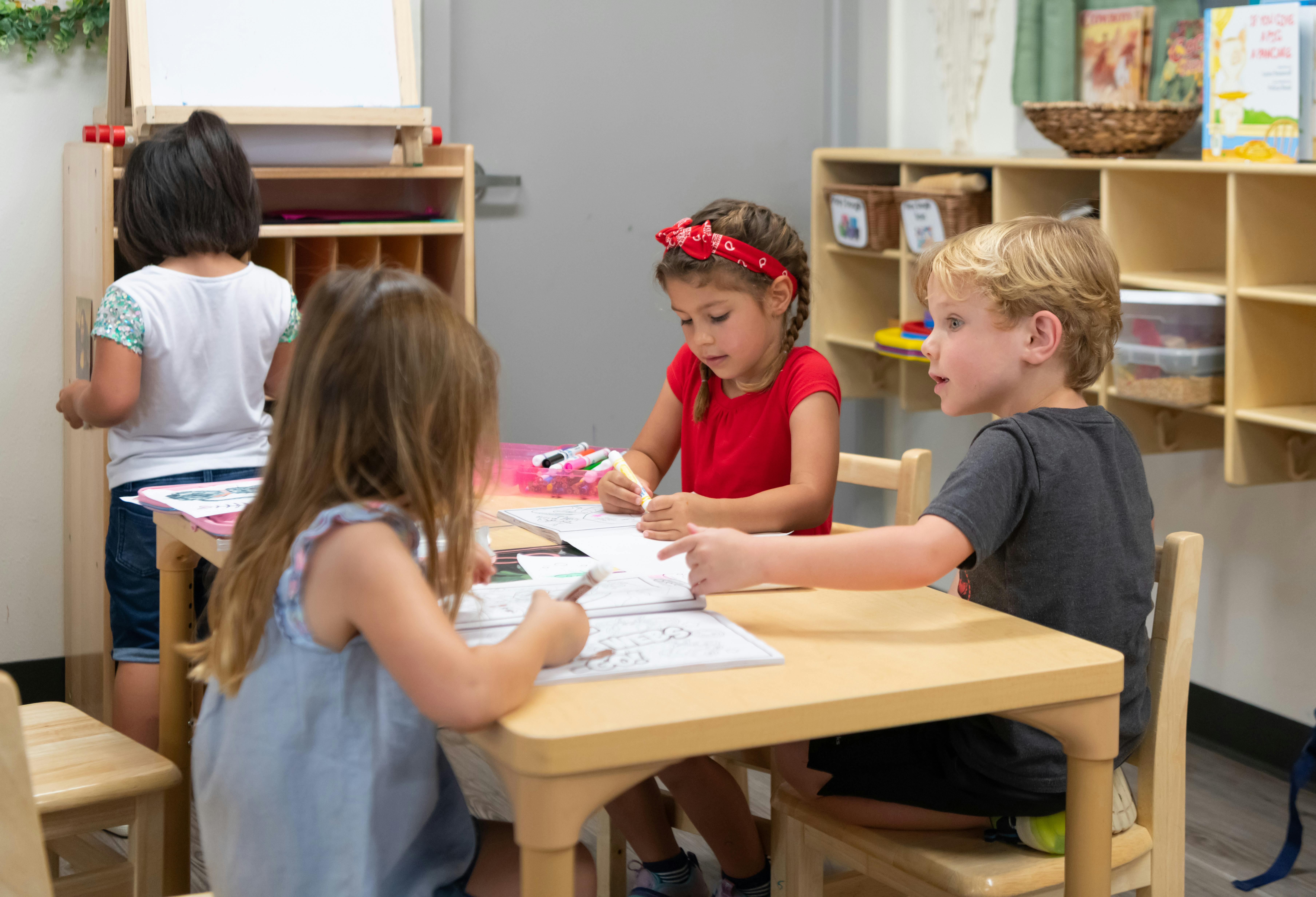 Children drawing and writing at a table in a classroom
