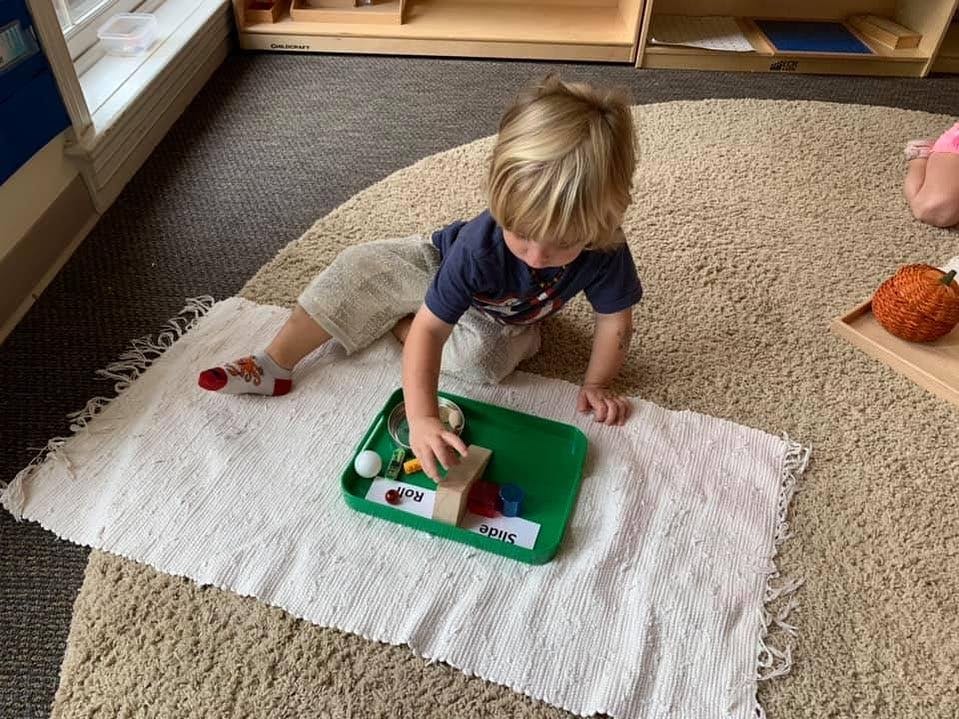 Child on floor playing with items in a green tray