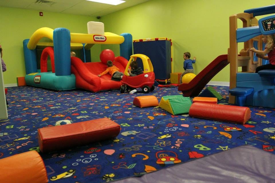 Children playing on indoor playground equipment with inflatable bounce house and slide