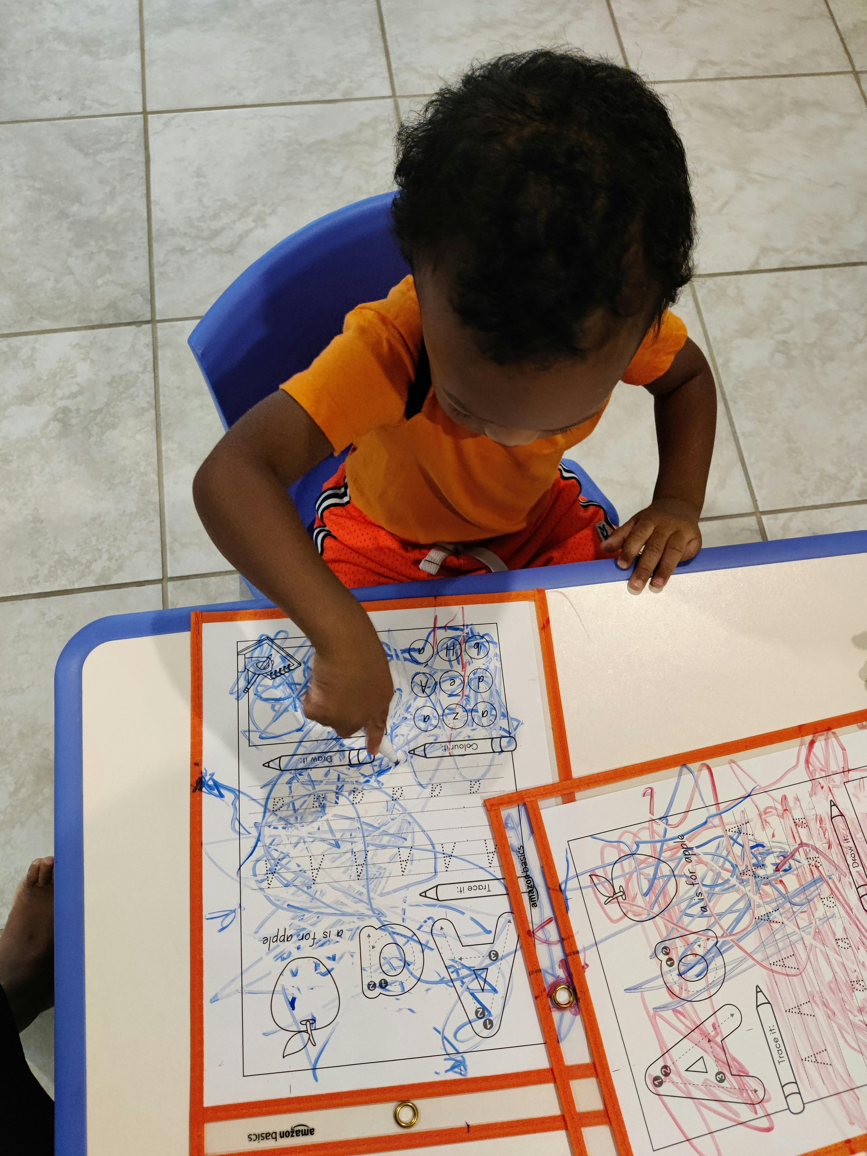Child sitting at a table drawing on paper