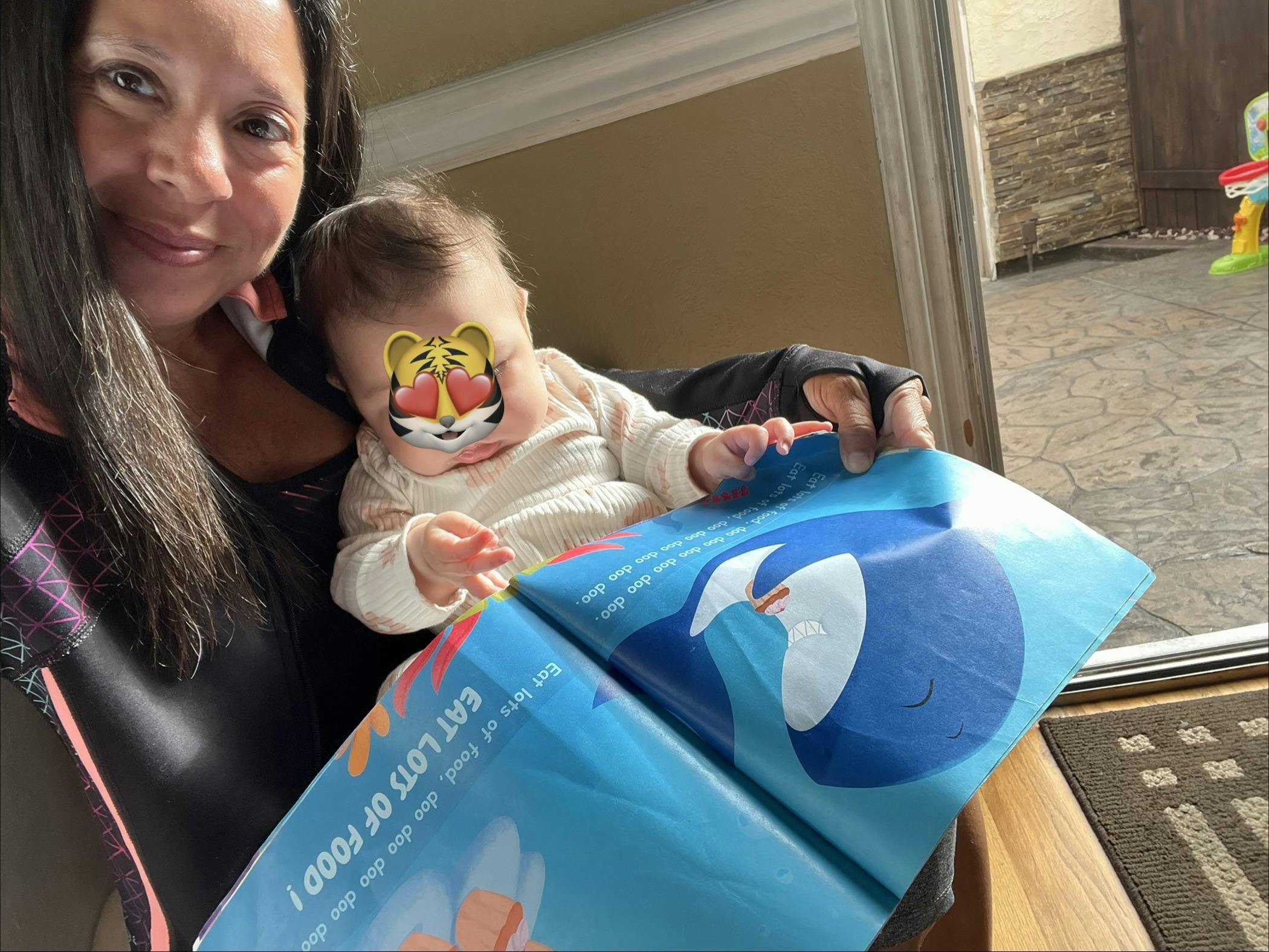 A person holding a child and reading an illustrated children's book