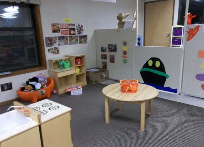 Playroom with small kitchen set, round table, and toys