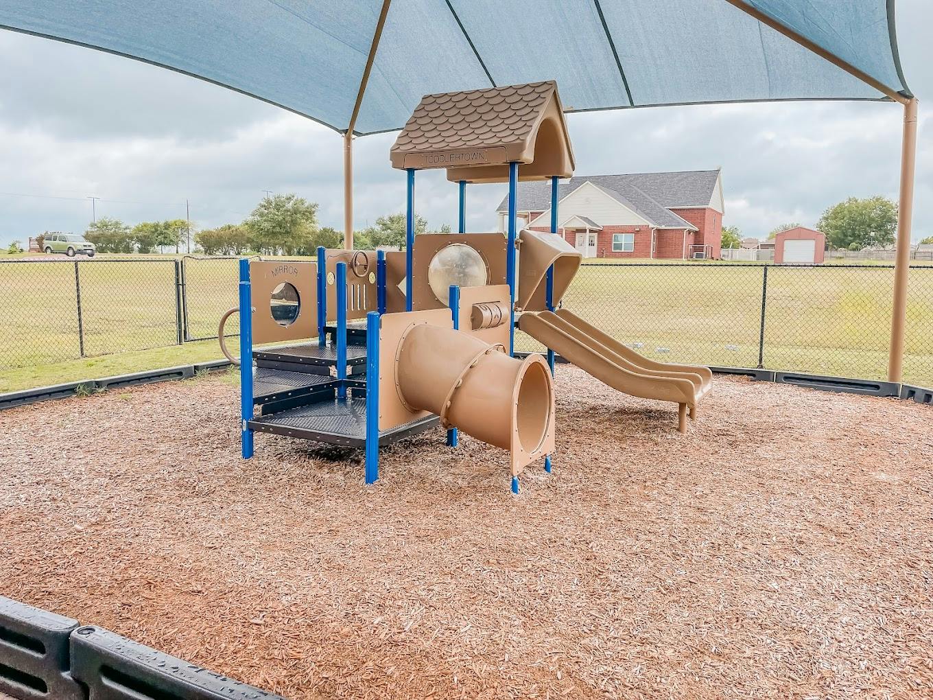 Playground structure with a tunnel and slide under a canopy