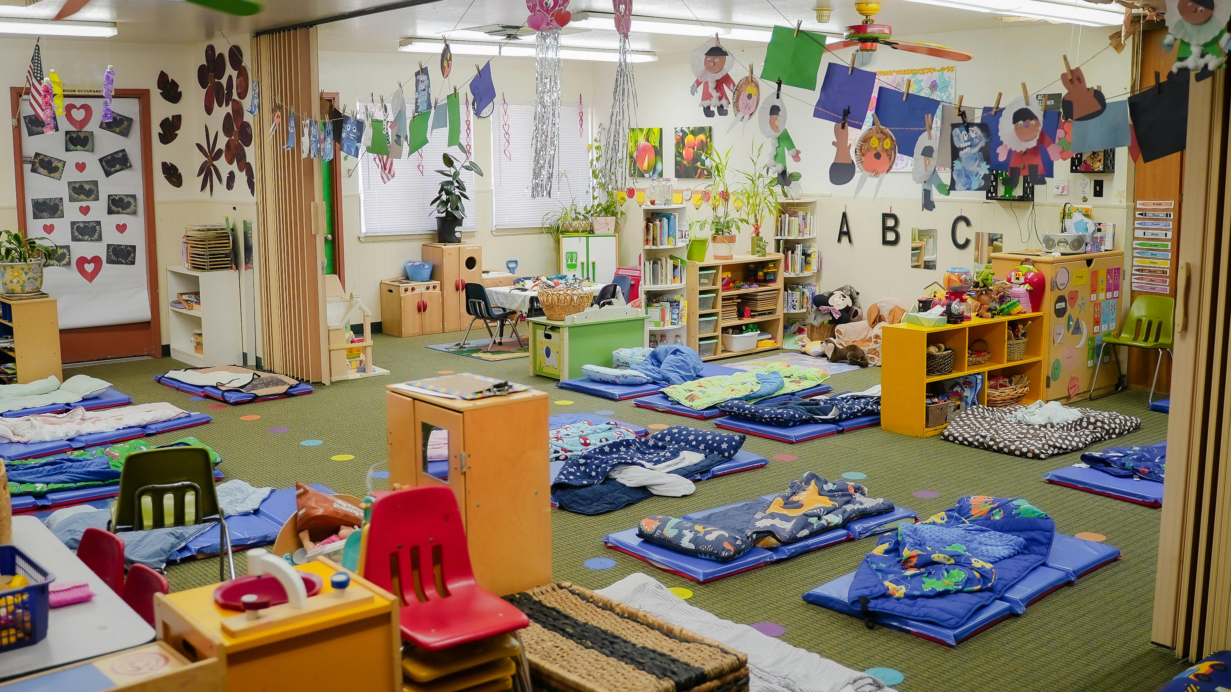 Classroom filled with nap mats on the floor and educational decorations
