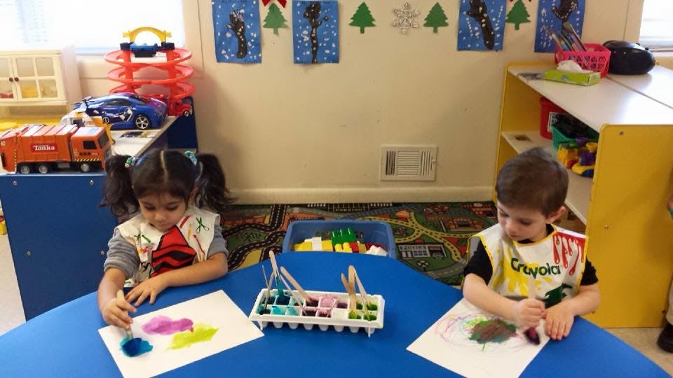 Two children painting at a table in a classroom