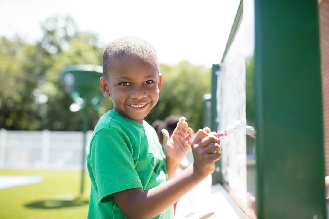 Child drawing on a board outdoors