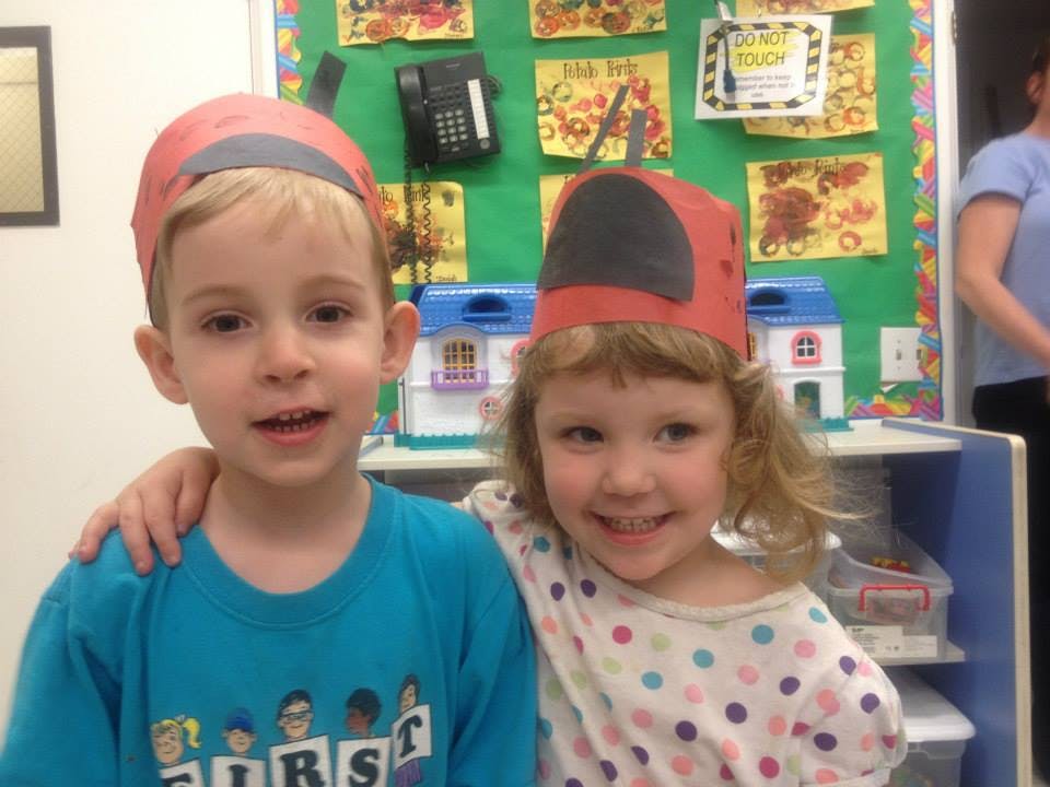 Two children wearing red paper hats