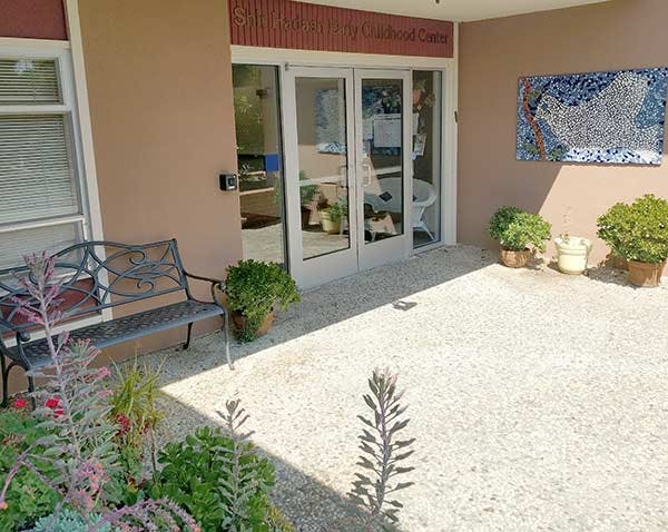 Building exterior with glass doors, a bench, and potted plants