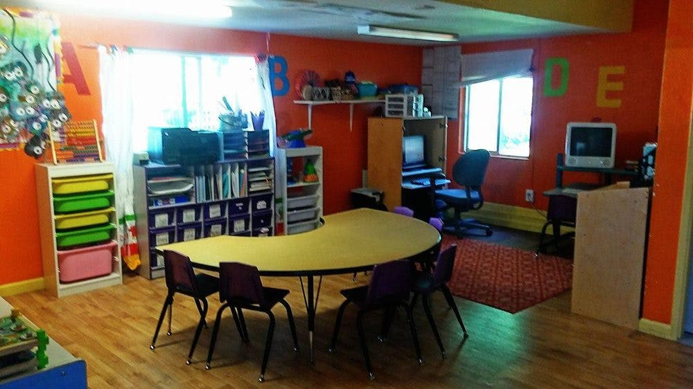 Classroom with a curved table and chairs, shelves, and windows