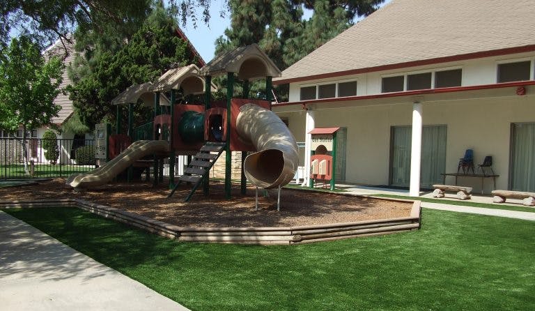 Playground with slides and artificial turf next to a building