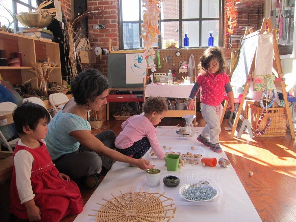Adult and two children playing with objects on a table