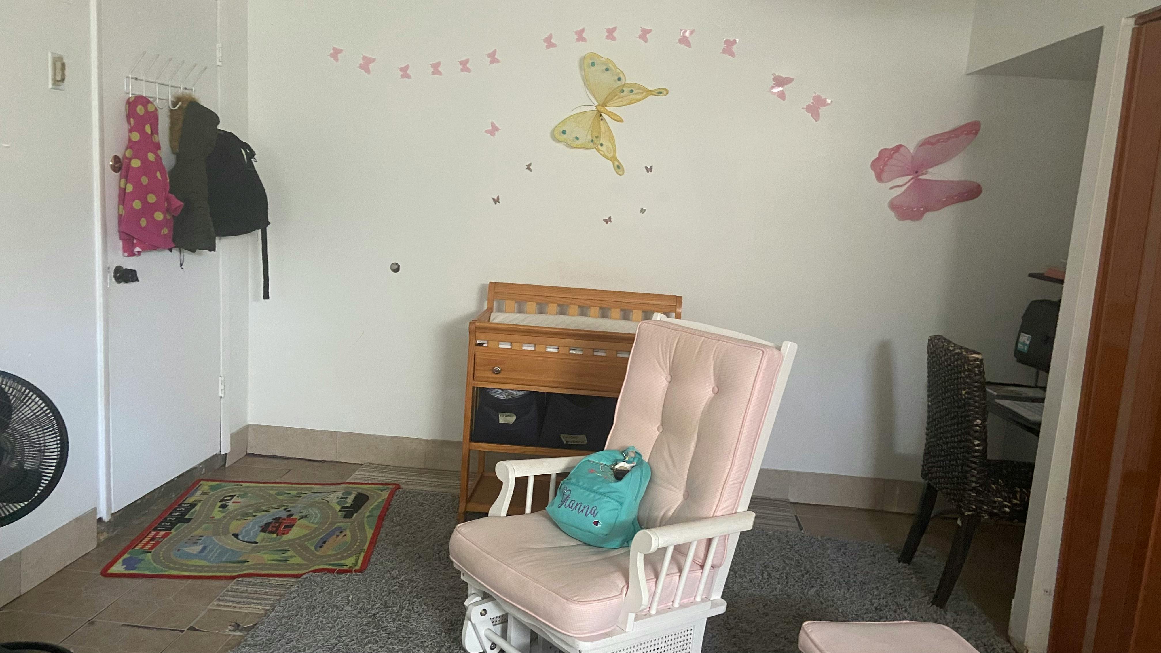 Nursery room with a rocking chair, changing table, and butterfly wall decals