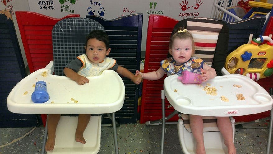 Two children in high chairs holding hands