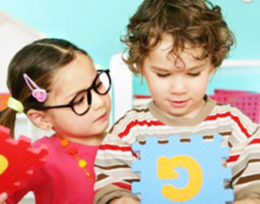 Two children playing with puzzle pieces