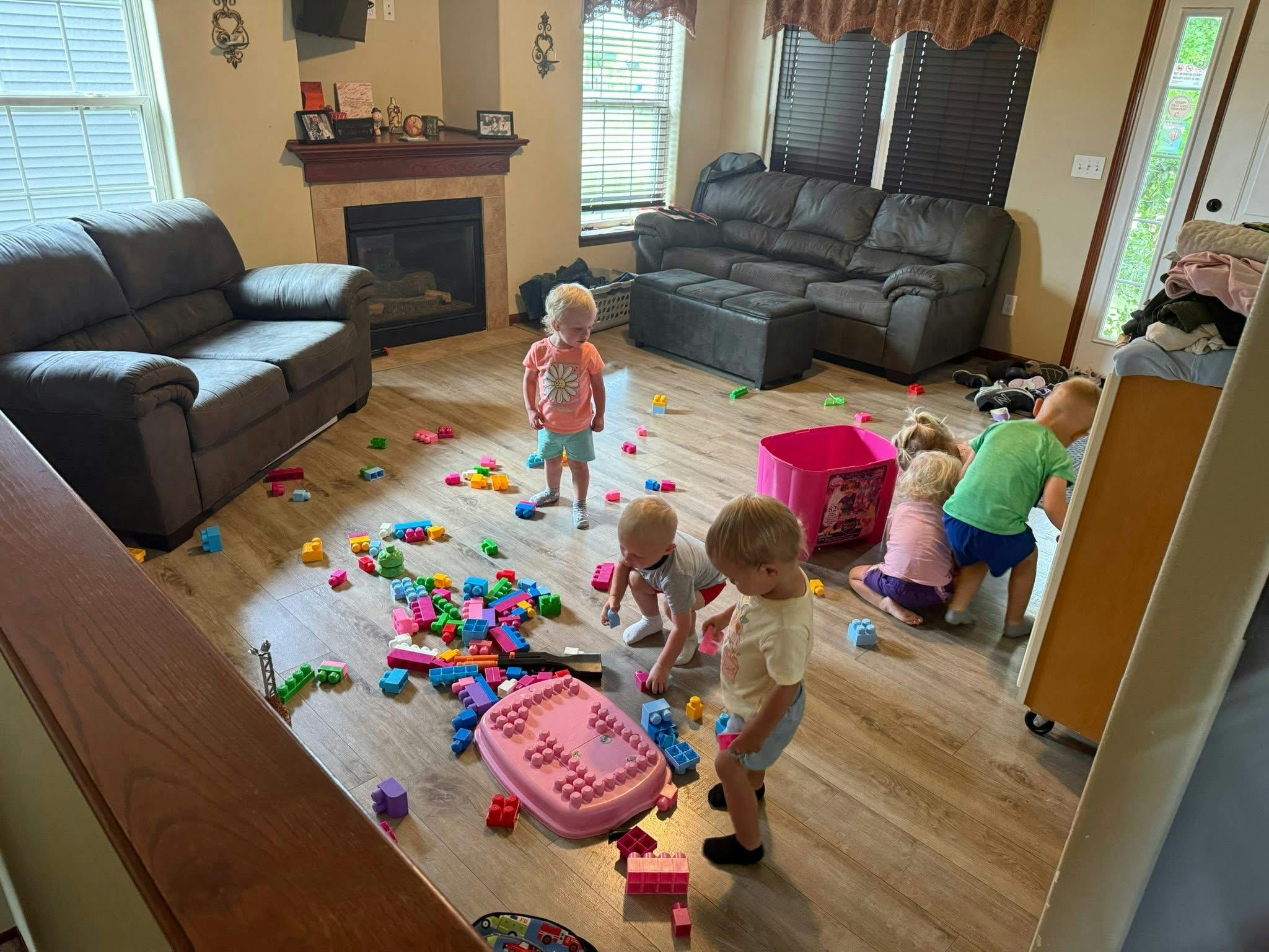 Multiple children playing with toys on a wooden floor in a living room