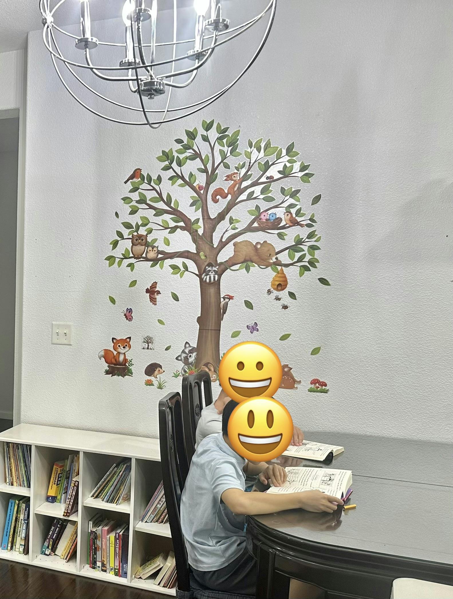 two people reading books at a table, with a tree wall decal behind them